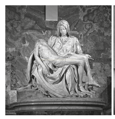 Fotografia em tons de cinza de uma escultura de mármore de uma mulher segurando um corpo no colo.