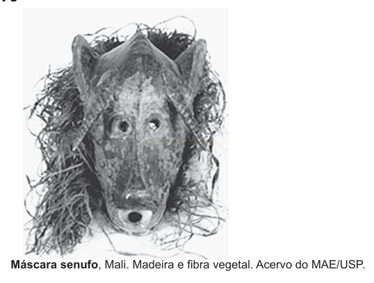 Fotografia em preto e branco de uma máscara africana de madeira com cabeça de animal e fibras vegetais ao redor.