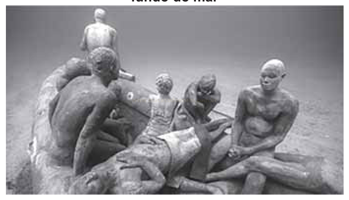 Fotografia subaquática de esculturas de figuras humanas dispostas no fundo do mar.