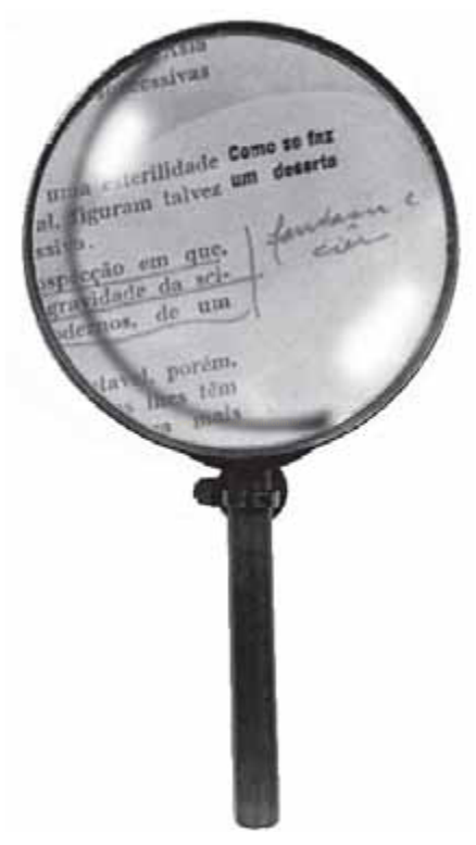 Fotografia em preto e branco de uma lupa sobre um texto datilografado, ampliando as palavras vistas pela lente.