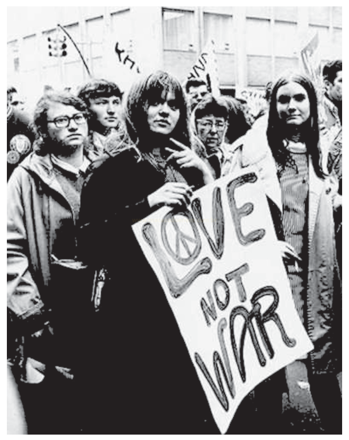 Fotografia em preto e branco de manifestantes jovens, com destaque para uma mulher segurando o cartaz LOVE NOT WAR.