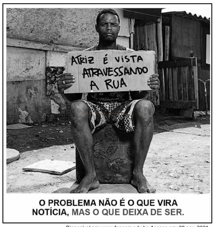 Fotografia em preto e branco de um homem segurando uma placa com a frase "Atriz é vista atravessando a rua", em ambiente externo simples.