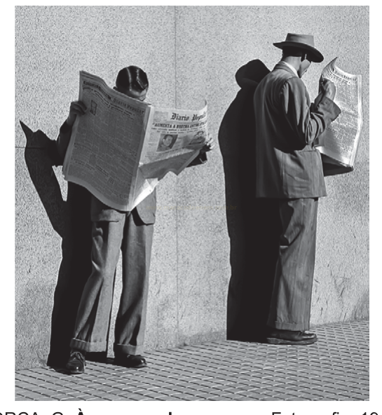 Fotografia em preto e branco de dois homens de terno lendo jornais de pé, junto a uma parede.