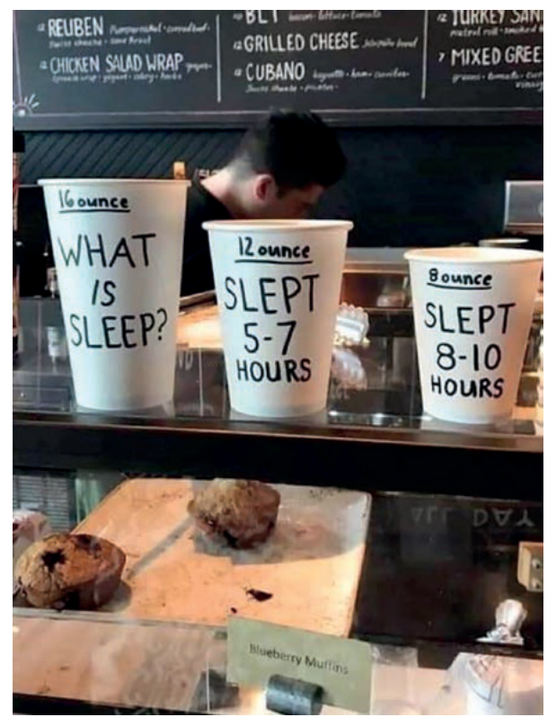 Fotografia de três copos de café com mensagens sobre horas de sono no balcão de uma cafeteria.
