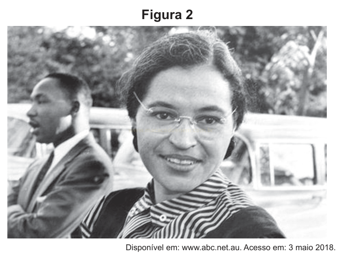 Fotografia em preto e branco com uma mulher negra sorrindo em primeiro plano e um homem de terno desfocado ao fundo.